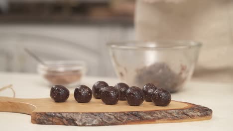 right to the left shot of homemade nutritious chocolate sweets placed onto a wooden cooking board in the foreground. making candies. healthy and tasty nutrition concept