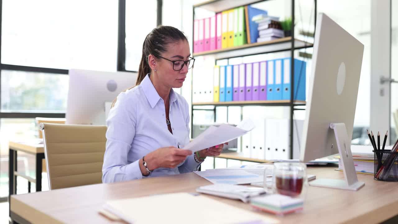 Woman working in office with paperwork and computer