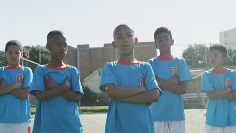 african american soccer kids in blue crossing arms and looking at camera in a sunny day