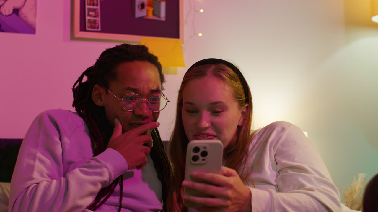 una pareja sonríe mientras miran su teléfono juntos