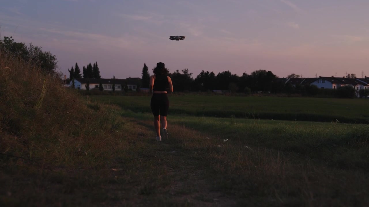 Donna attiva che corre di sera e piccolo drone impostato in modalità inseguimento, Cechia