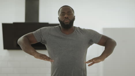 focused black man dancing at open kitchen. young dancer moving upper body home