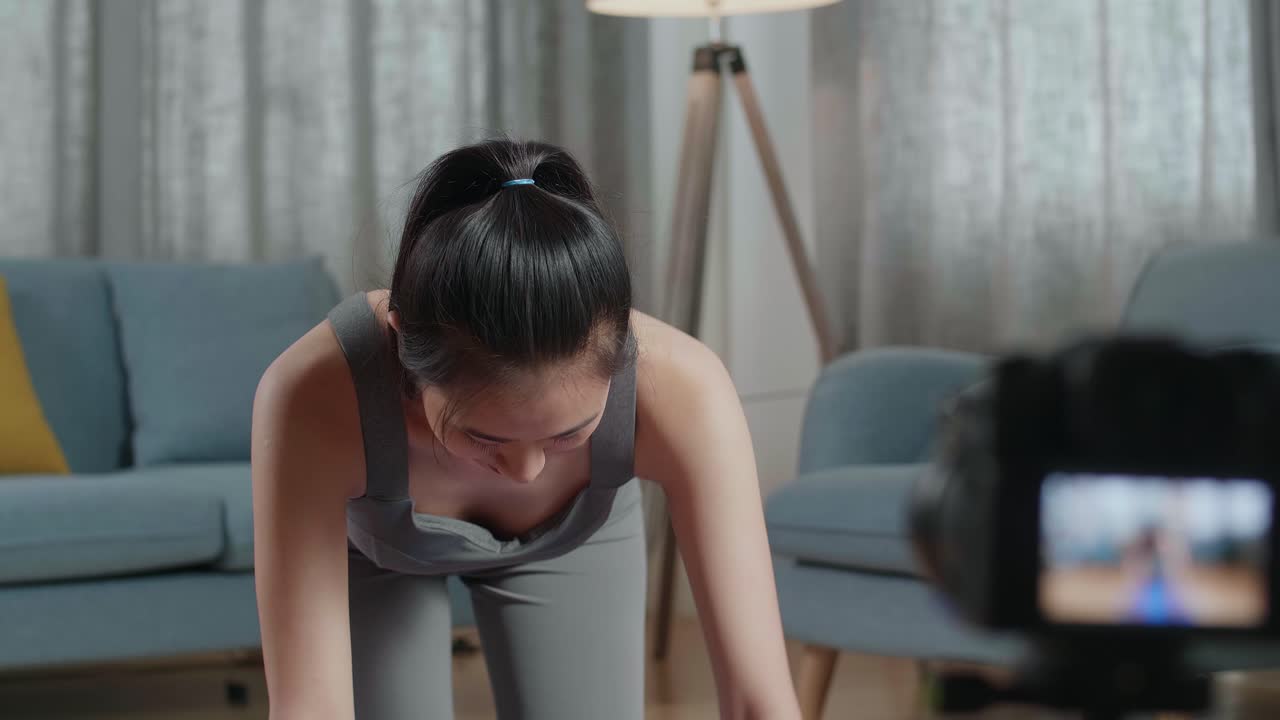 스포츠 옷을 입은 젊은 아시아 트레이너 여성이 카메라에 대화하고 집에서 가르치는 운동을 녹음하는 동안 균형 잡는 테이블 포즈에서 요가를합니다.
