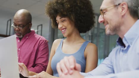 Diverse-male-and-female-business-colleagues-smiling-and-using-laptop