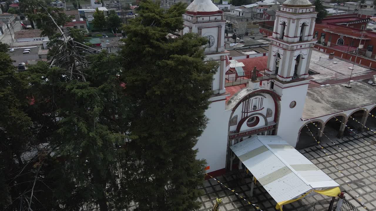 iglesia en órbita de drones volando en la vista panorámica del techo al atardecer con arquitecturas urbanas que pasan detrás de los árboles en méxico