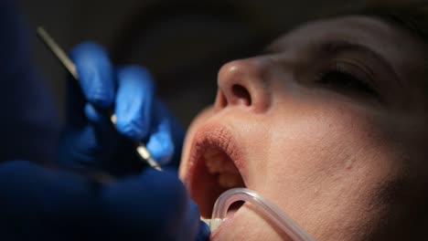 orthodontist performs dental care on female patient at dental clinic mouth close up