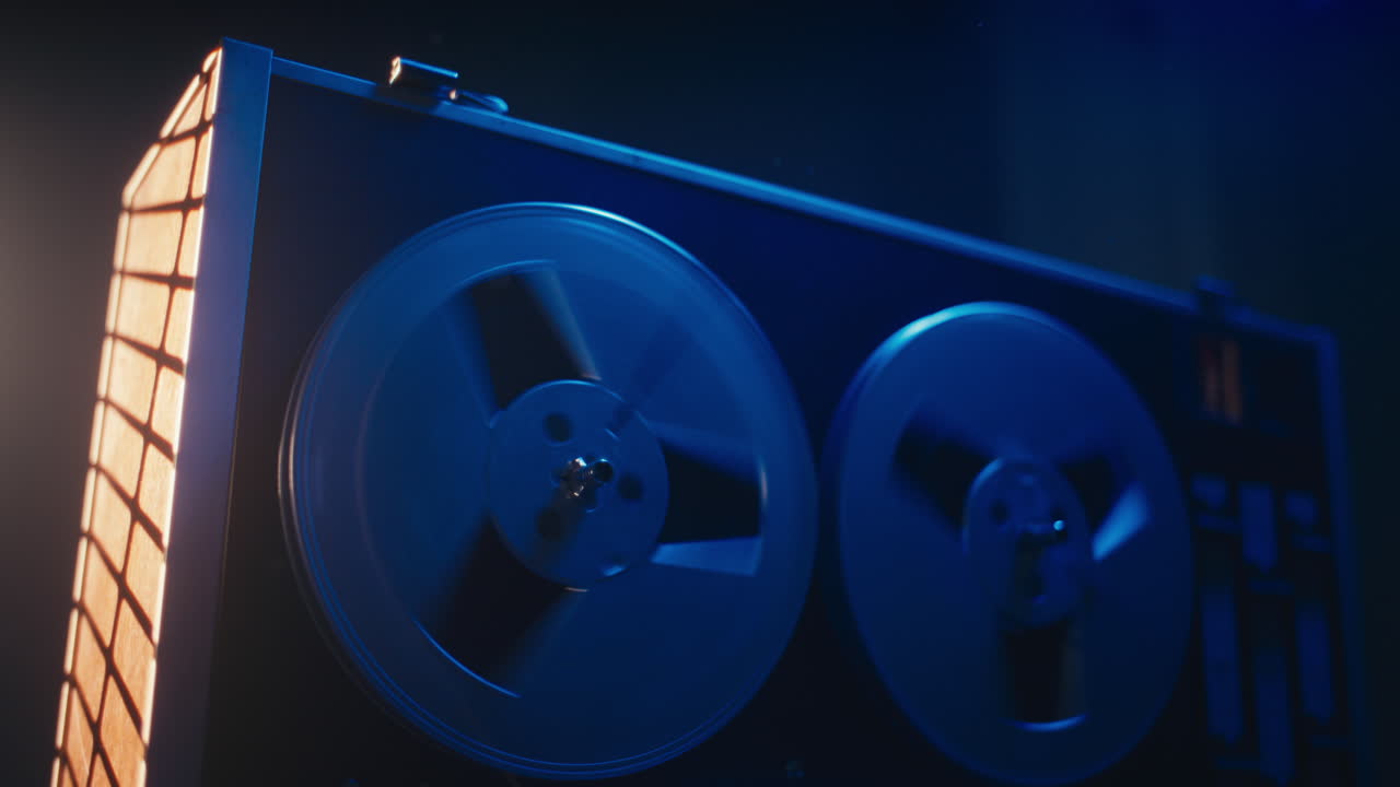 A vintage tape recorder spinning spools in a blue light