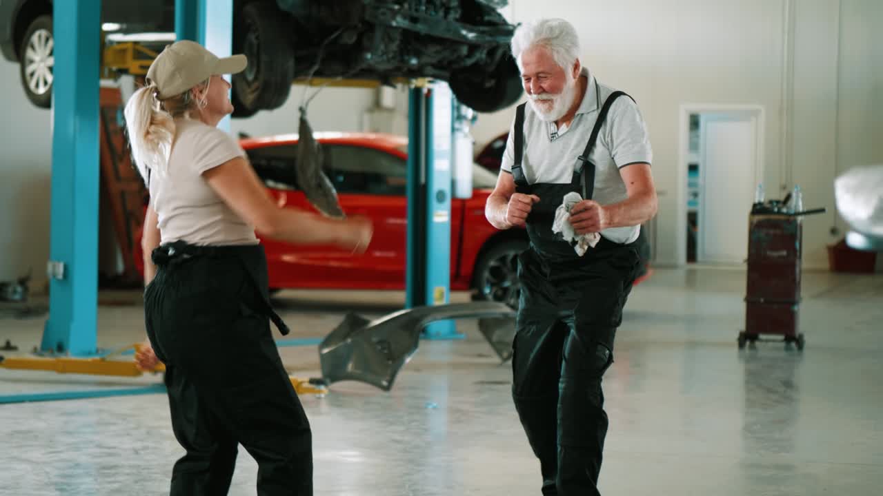 hombre y mujer adultos en uniforme bailando en el taller de reparación.