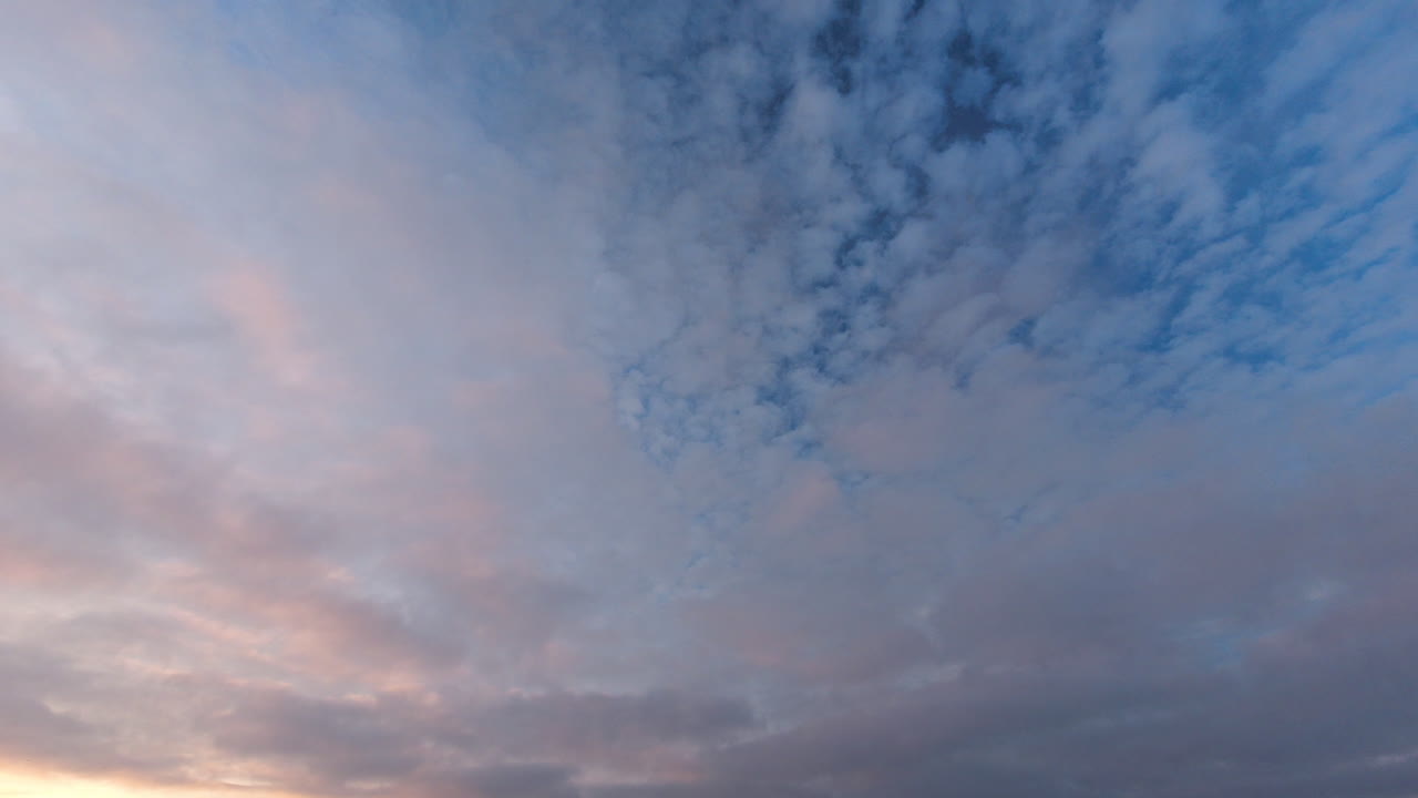 석양에 서로 다른 방향으로 표류하는 구름의 시간 경과