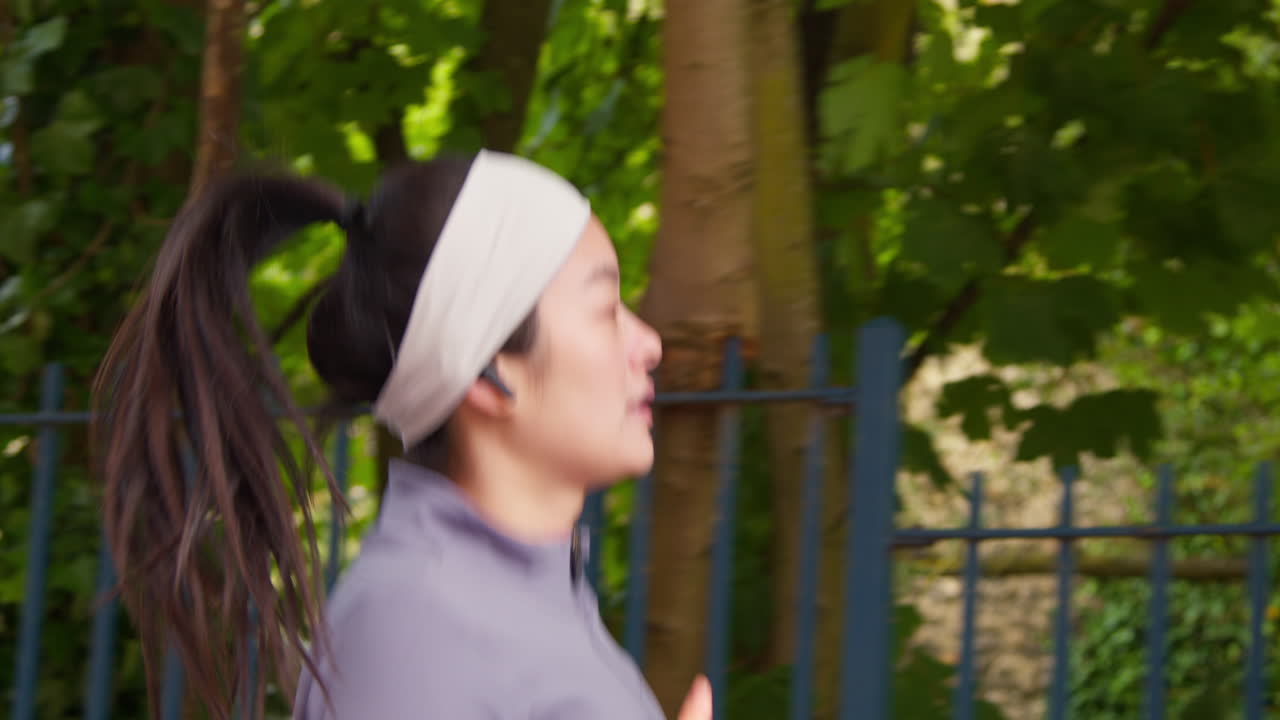 vista lateral de cerca de una mujer joven haciendo ejercicio corriendo por la calle urbana usando auriculares inalámbricos 1