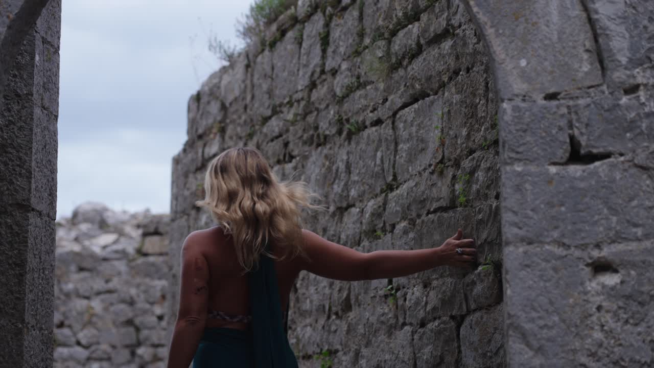 Caucasian female tourist walking inside the fortification of Rozafa Castle during the day near Shkoder, Albania, medium shot