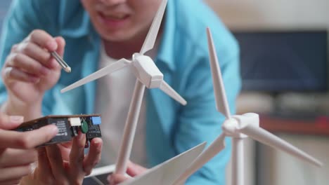 close up of asian man and woman discuss about work with circuit board, wind turbine and laptop computer
