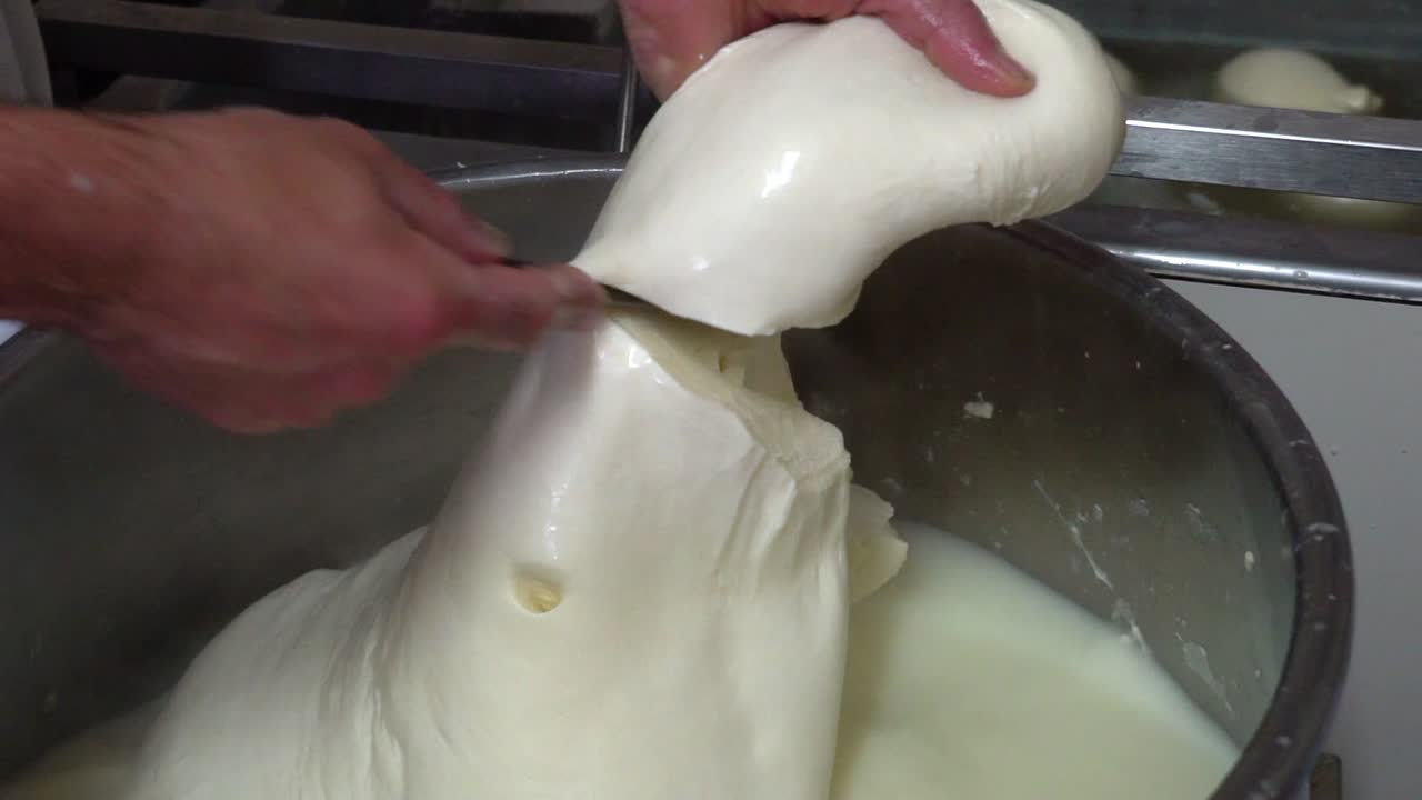 Slicing a big chunk of cheese and dipping it into hot water