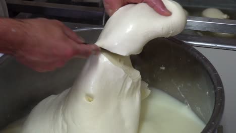 Slicing-a-big-chunk-of-cheese-and-dipping-it-into-hot-water