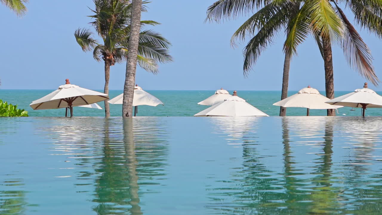 해변에 있는 빈 인피니티 풀과 하얀 파라솔