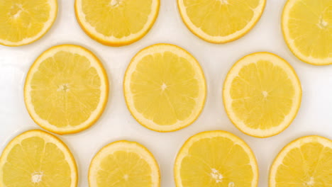 en cámara lenta salpicaduras de agua verter agua sobre un hermoso fruto cítrico jugoso muchos limones en un fondo blanco