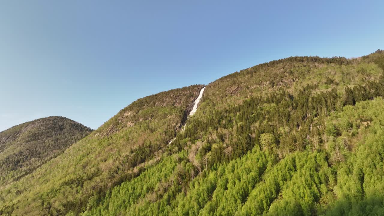 водопад кирелви, падающий с вершины горы в викойри в норвегии - воздушный снимок в вечернем солнечном свете, глядя на гору с рекой