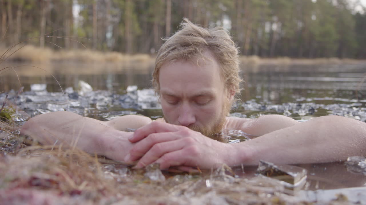 увеличение - купальщик на льду сосредоточен на осознанном дыхании, сидя в замерзшем озере