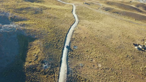 aerial view of a car driving along a dirt road through the andes mountains