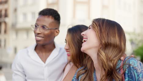 three smiling friends walking together in a city