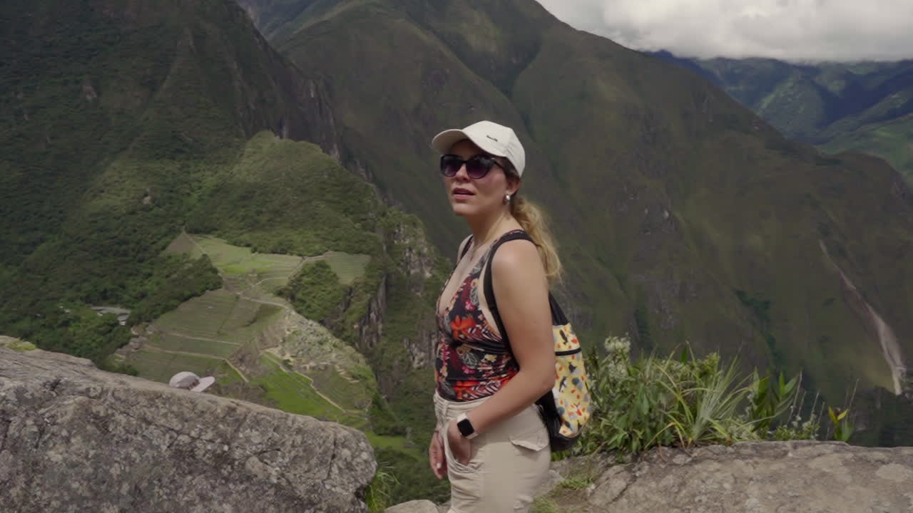 Tourist woman on top of Huayna Picchu Mountain, with Machu Pichu in background. Independent Solo traveler