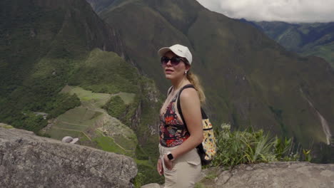 tourist woman on top of huayna picchu mountain, with machu pichu in background. independent solo traveler
