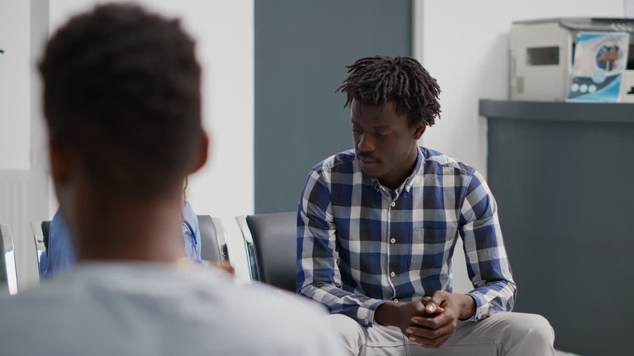 Profesjonell arbeider forklarer medisin til mannlig pasient i sykehuslobbyen