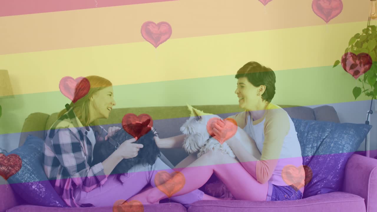 심장 에모지와 무지개 발의 애니메이션 개와 함께 백인 여성 커플