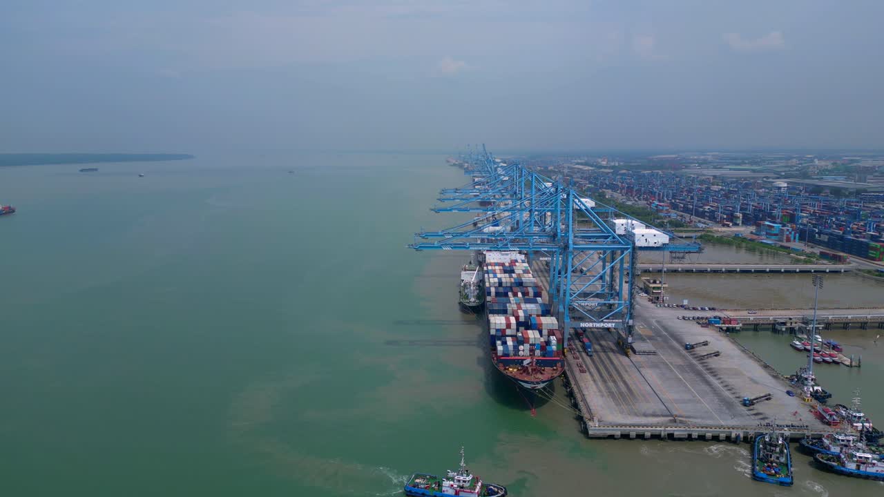 large container ship docked at Northport terminal with gantry cranes, illustrating global logistics and maritime trade. Unbelievable aerial view fly push forward drone