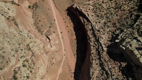 Eine-Filmische-Draufsicht-Auf-Das-Capitol-Reef,-Durch-Das-Eine-Straße-Führt-Und-Auf-Der-Ein-Undeutliches-Auto-Entlang-Fährt