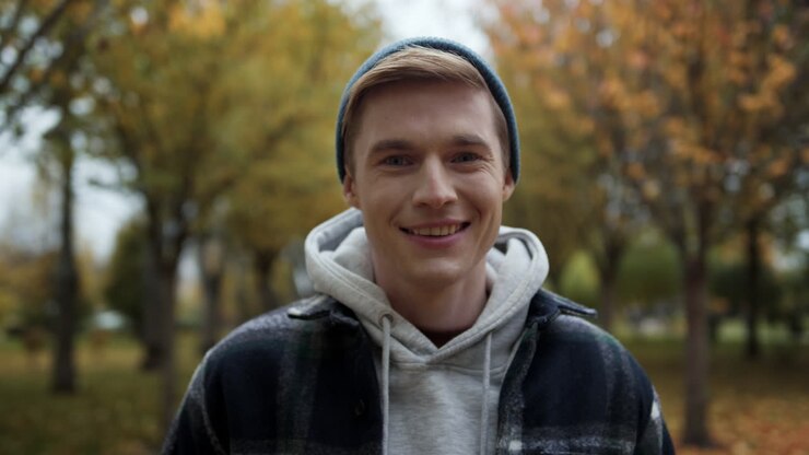 Cheerful man posing for camera in autumn park