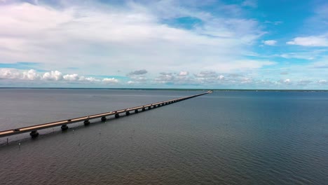 Vista-Aérea-Volando-Cerca-Del-Agua-Mirando-El-Puente-De-La-Bahía-Que-Conecta-El-Destino-Con-Niceville,-Florida