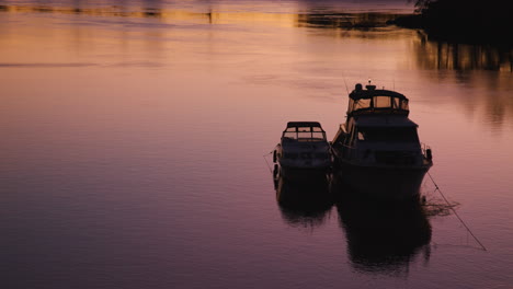 a boat sits on the river at sunset and rocks back and forth due to the current swiftly flowing past it