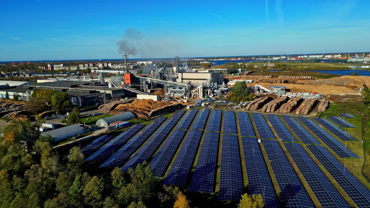 Aerial view of a large solar panel field close to a industrial plant, sunny day