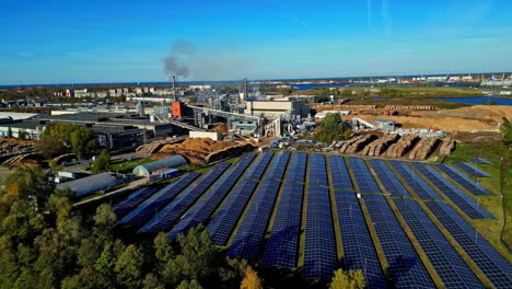 aerial view of a large solar panel field close to a industrial plant, sunny day