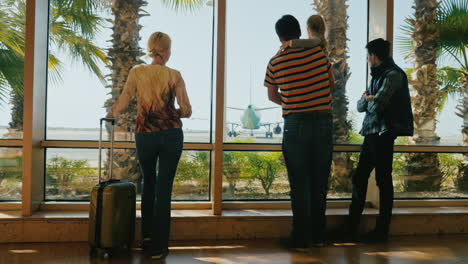 una famiglia di quattro persone guarda l'aereo nel terminal dell'aeroporto