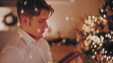 handsome man reading book in illuminated home during christmas