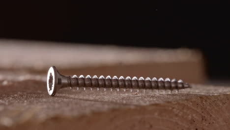 long metal screw fall on wooden board with blurry background