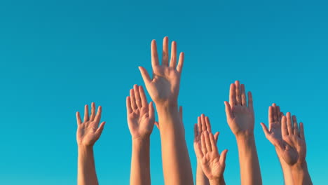 Raised-hands-against-blue-sky