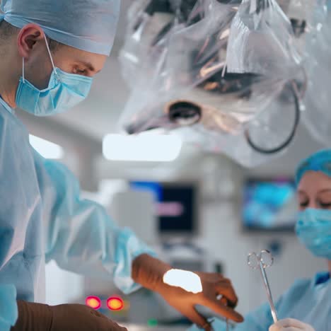 doctor and nurse in operating room. surgeon together with female assistant in blue medical uniform and mask conduct an operation on microscope background.