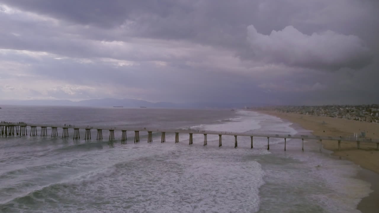 fuertes olas de tormenta de verano pasando por el muelle de la playa de manhattan en california, antena