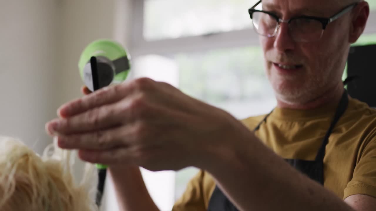 vista lateral peluquero secando el cabello de una mujer