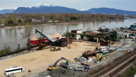 loading sand barge and trans mountain pipeline alongside fraser river in port kells, surrey, bc, canada