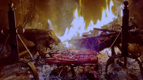 delicious sausages roasting on fireplace grill with fire burning in background, close-up