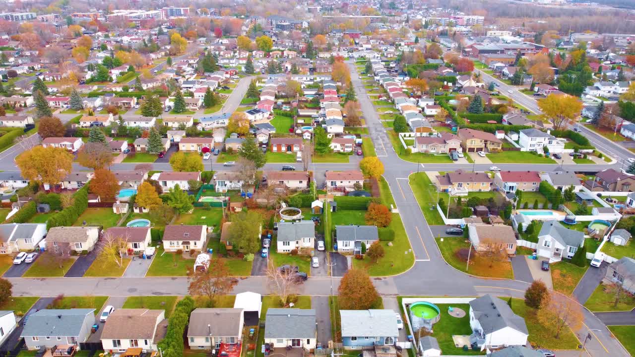 Panning left aerial view of a large residential neighborhood in Estrie, Québec, Canada, during the autumn season. Captures the suburban landscape with houses, streets, and colorful fall foliage