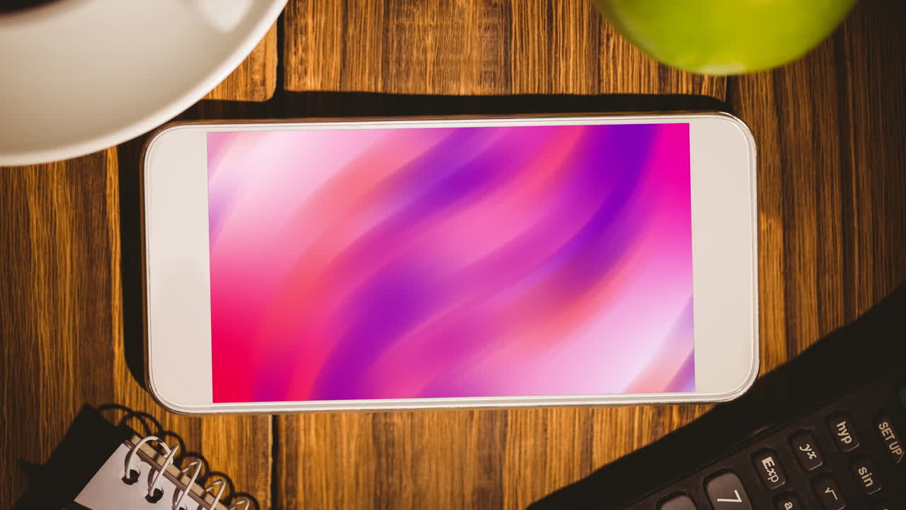 animación de un teléfono inteligente con formas en movimiento rosadas en la pantalla en un escritorio de madera.