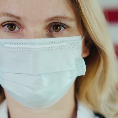 Portrait-Of-An-Attractive-Young-Doctor-Against-The-Backdrop-Of-America's-Flag