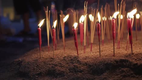 Toma-Panorámica-De-Velas-Rojas-Encendidas-Y-Varitas-De-Incienso-En-El-Suelo