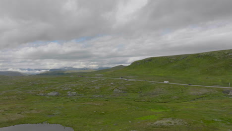 Green-landscape-of-Hardanger-Plateau-in-Norway,-road-cutting-through