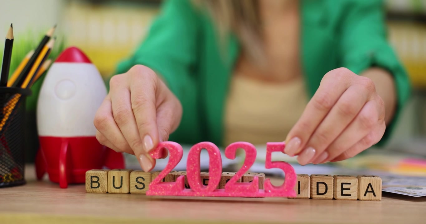Manos de mujer ponen el cartel 2025 antes de la frase 'idea de negocio'.